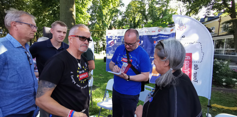 Prof. Adam Bodnar podpisuje się w broszurze z Konstytucją RP. 