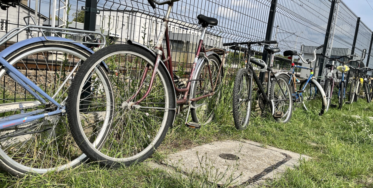 wokół pełno parkingów dla aut, a rowerzyści przypinają się do siatki